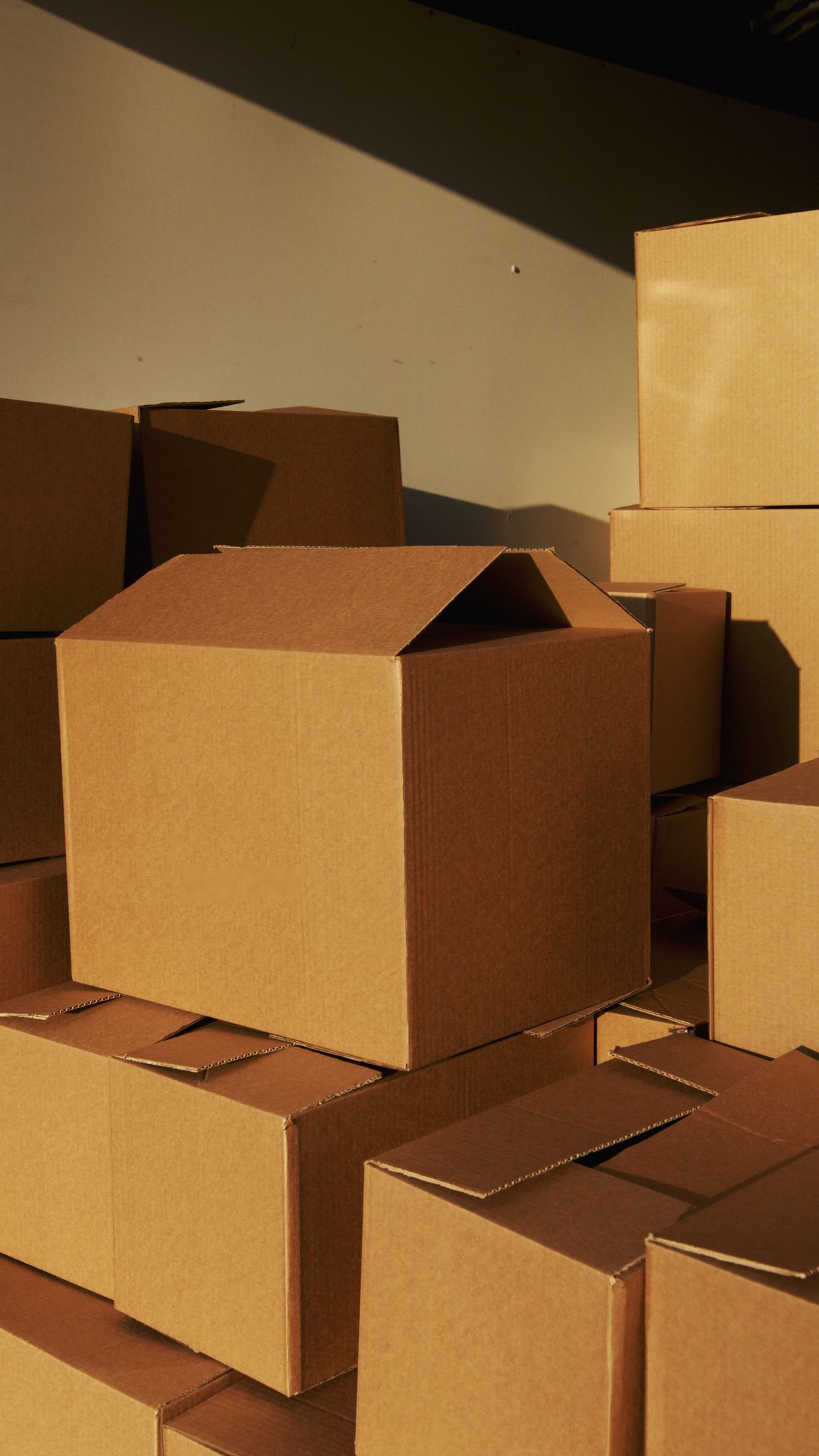 Stacks of plain kraft cartons in a warehouse — bulk production has to match the booth sample, every time